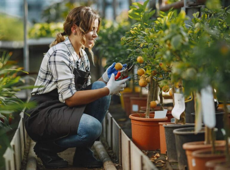 A woman kneeling down in the middle of a garden.